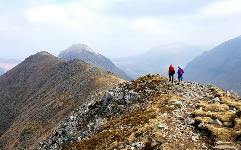 Two people hiking on top of a grassy mountain