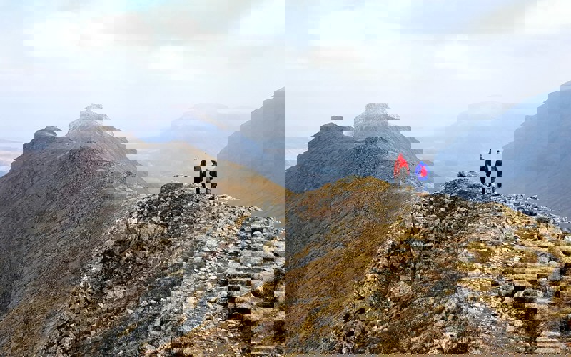 Two people hiking on top of a grassy mountain