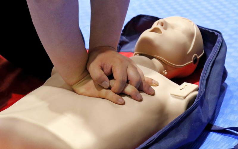 Hands performing CPR on a training dummy