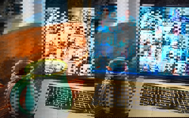 China mug in front of a laptop screen showing an online meeting
