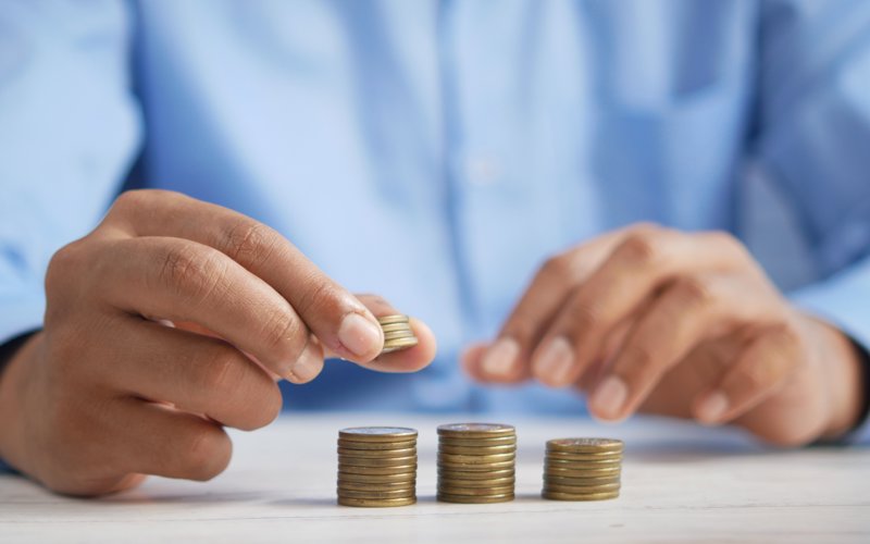 Person counting gold coins into three piles