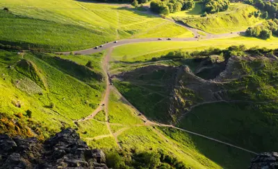 Criss-crossing paths in a green, hilly landscape with rocks and gorse