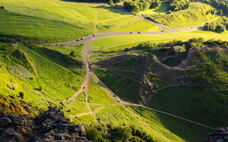 Criss-crossing paths in a green, hilly landscape with rocks and gorse