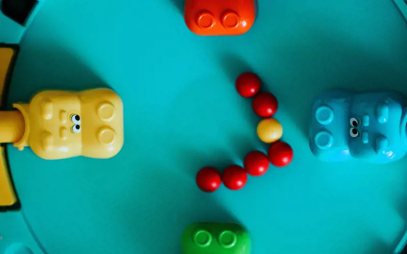 Coloured plastic hippo heads surround red and yellow marbles on a game board.