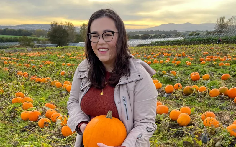 Vicki Madden stands in a field of pumpkins, holding a pumpkin