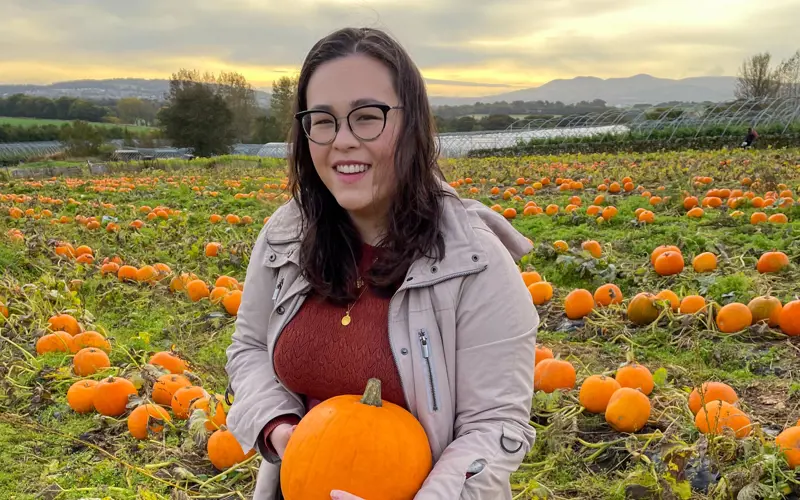 Vicki Madden stands in a field of pumpkins, holding a pumpkin