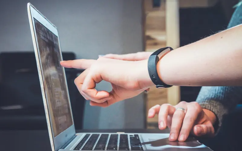 A hand pointing at a laptop screen