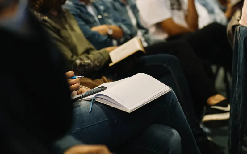 A row of people seated with pens and open notepads