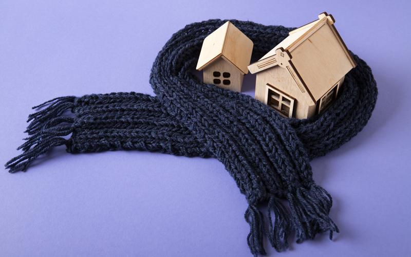 Two small wooden toy houses are surrounded by a thick navy scarf