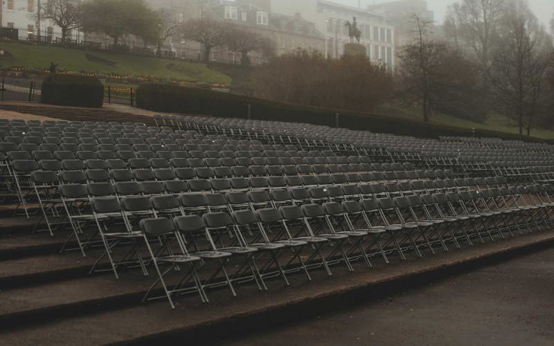 Rows of empty folding chairs in Princes Street Gardens in the fog
