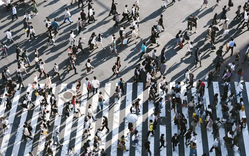 A large and very busy zebra crossing with people crossing left and right