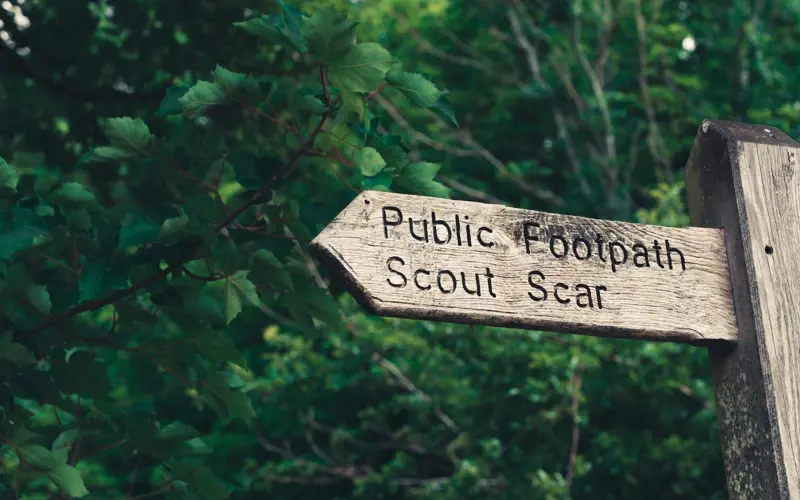 A wooden public footpath sign pointing to Scout Scar