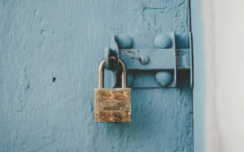 An old padlock attached to blue wood door