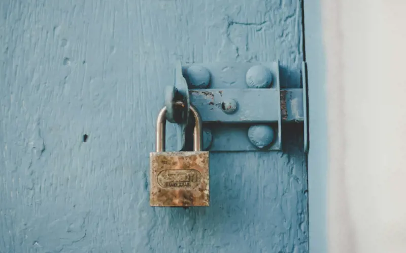 An old padlock attached to blue wood door