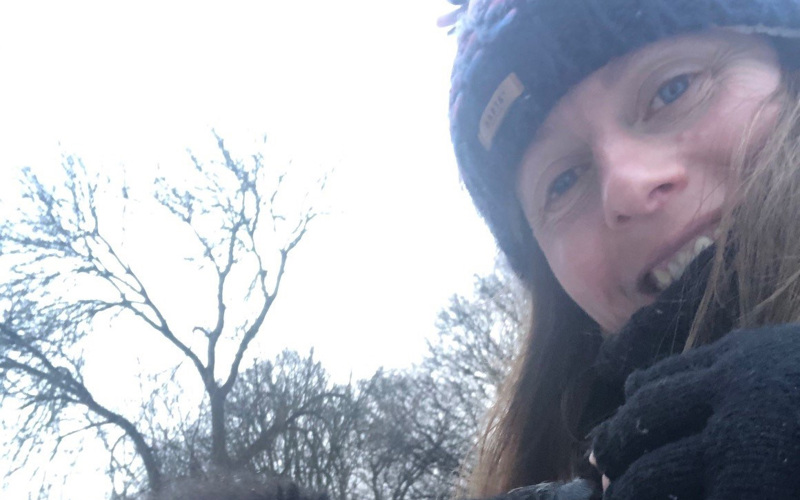 Shona McElroy in a hat and gloves with a black dog.