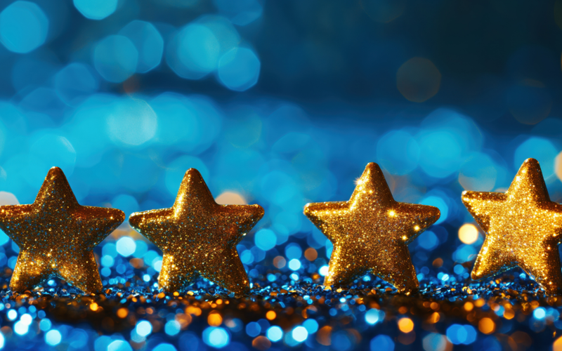 Four gold stars in a row with blue glittery background