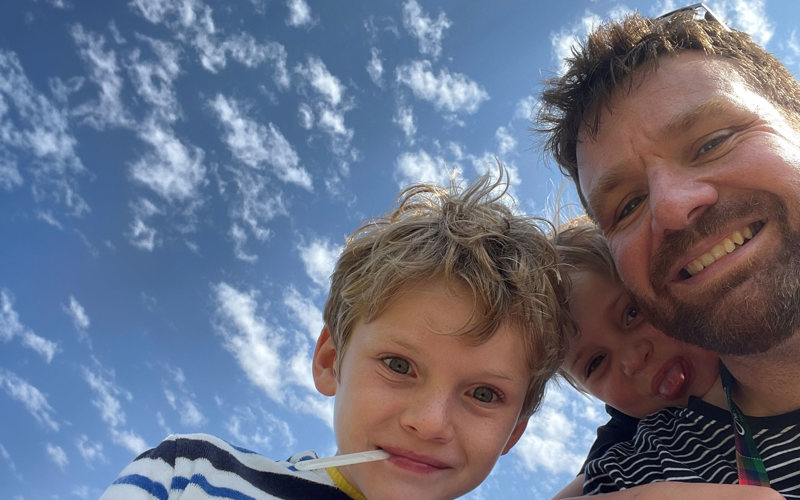 Selfie of Hugh Wallace and his two children with a blue sky background