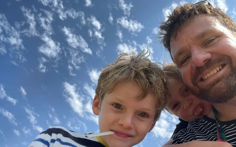 Selfie of Hugh Wallace and his two children with a blue sky background