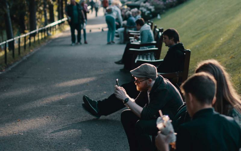 People sitting on benches in Princes Street Gardens in the evening sun