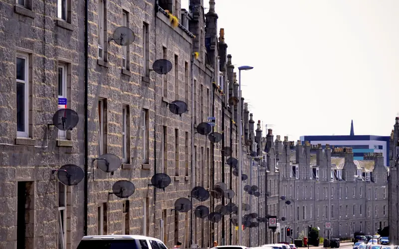 A row of tenement buildings in Aberdeen with satellite dishes on the outside.